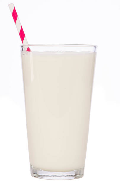 A glass of milk in a clear glass with a red and white straw