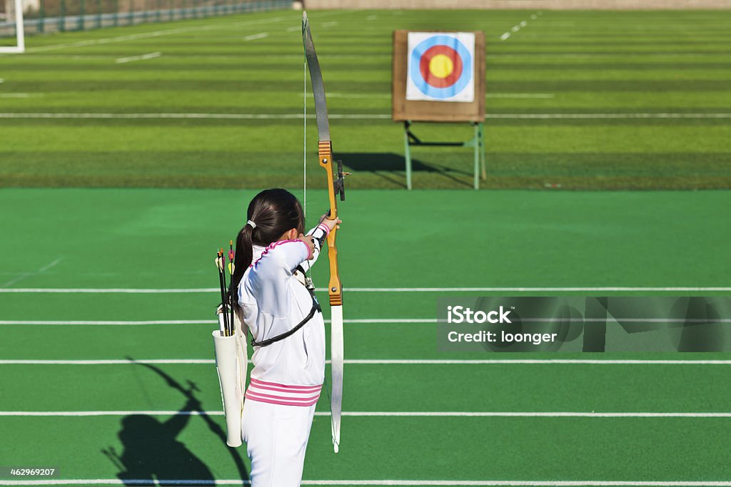 teenage girl archer aiming at target East asian teenage girl archer aiming at target in the playground Archery Stock Photo