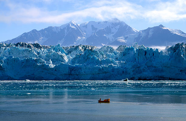 Hubbard Glacier Runabout The Hubbard Glacier in southeast Alaska provides the backdrop for a comparatively tiny runabout boat collecting ancient glacial ice, which will soon become an ice sculpture aboard a cruise ship. seward alaska stock pictures, royalty-free photos & images