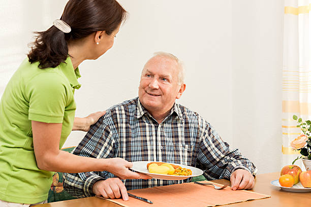 istock Caregiver giving senior man lunch in the kitchen 462969857