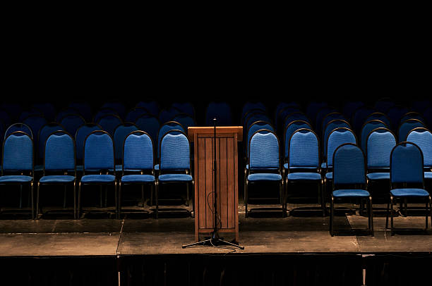 Conference hall Rows of blue chairs on stage behind a podium shareholders meeting stock pictures, royalty-free photos & images