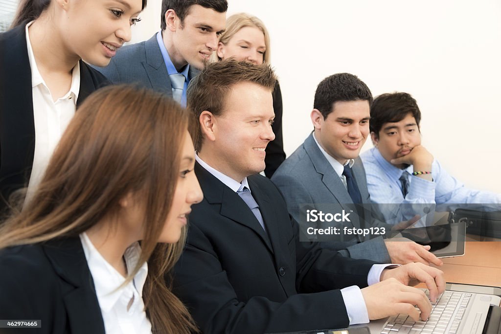 Business people video conference on laptop during meeting. Group of multi-ethnic business people use laptop and digital tablet during an office meeting.   20-29 Years Stock Photo