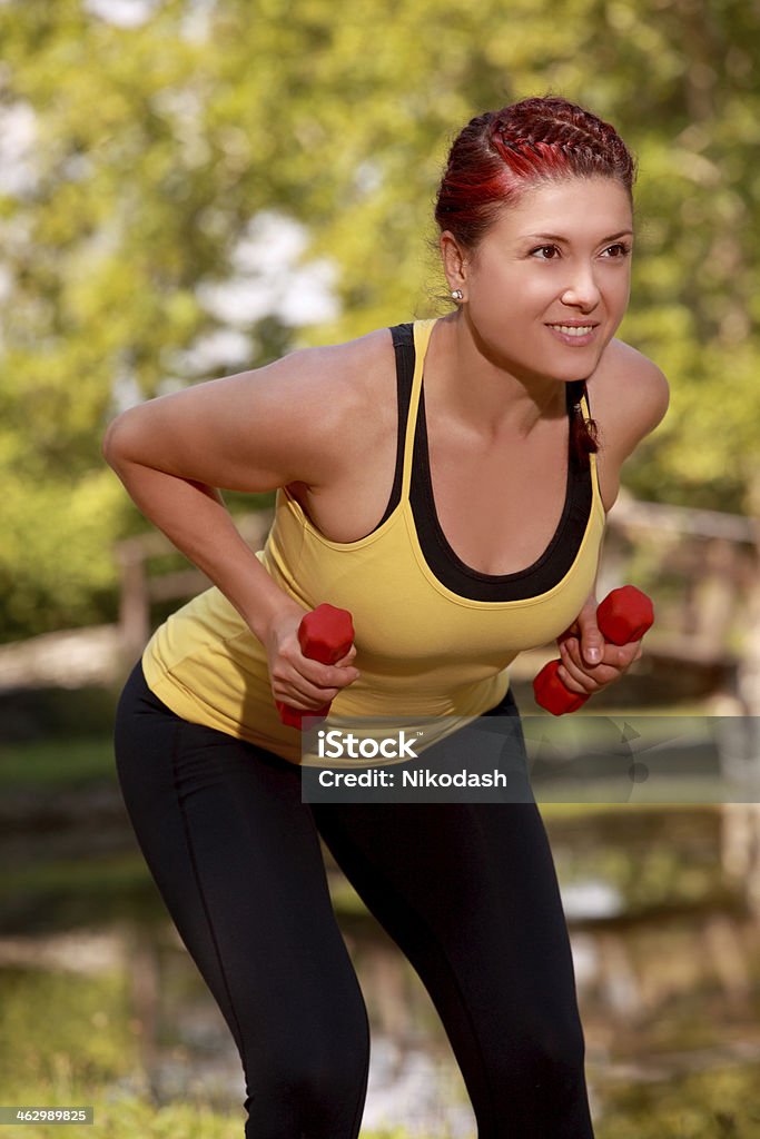 Woman exercises in park with set of wights smiling Young Woman exercises in park with set of wights smiling Active Lifestyle Stock Photo