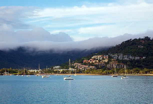 Seaside township of Airlie Beach in Queensland Australia photographed early in the morning with fog rolling in over the mountains.