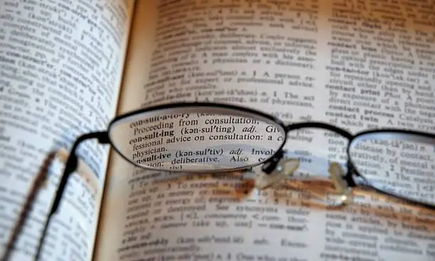 Glasses with the focussed word 'consulting' in a very old dictionary