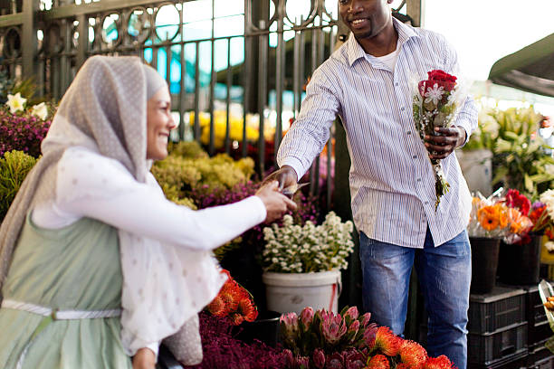 giovani donne vendere fiori di un africano maschio. - men african descent giving flower foto e immagini stock