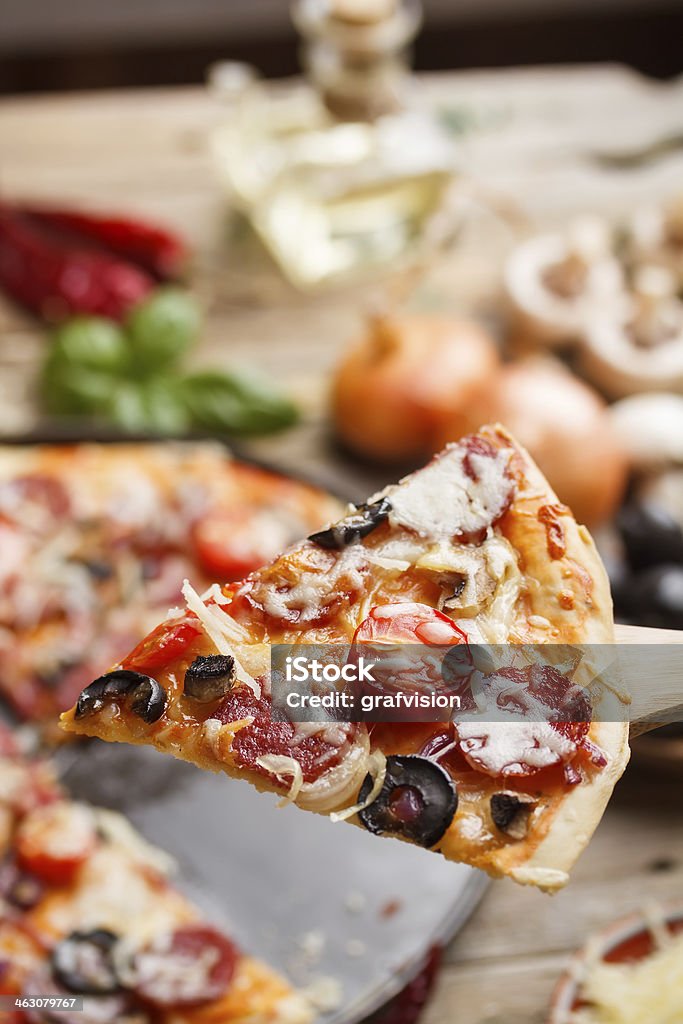 Rustic pizza Rustic pizza topped with salami, tomato and olives Backgrounds Stock Photo