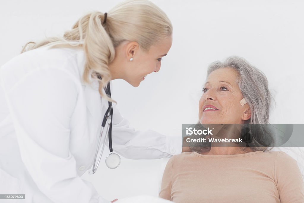 Doctor taking care of elderly woman Doctor taking care of elderly woman in bed 20-29 Years Stock Photo