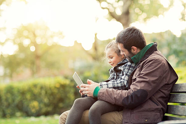 istock Father and daughter  in the park  looking to a tablet 463080855