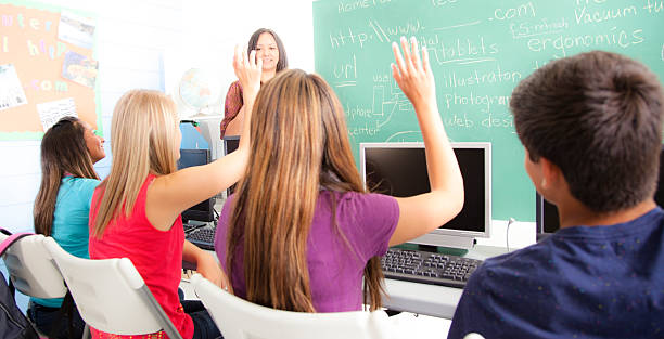 Education: Students in computer lab with instructor. Teen students work on research in computer lab with teacher.   teenage high school girl raising hand during class stock pictures, royalty-free photos & images