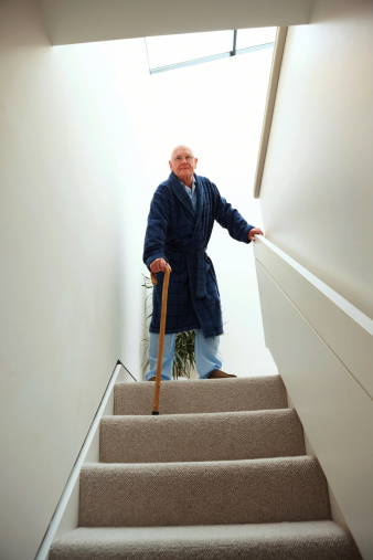 Elderly man walking down stairs using a cane