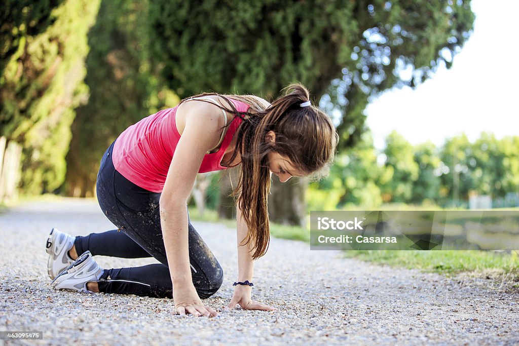 Fall Young woman falling while jogging outdoors on a gravel road. Falling Stock Photo