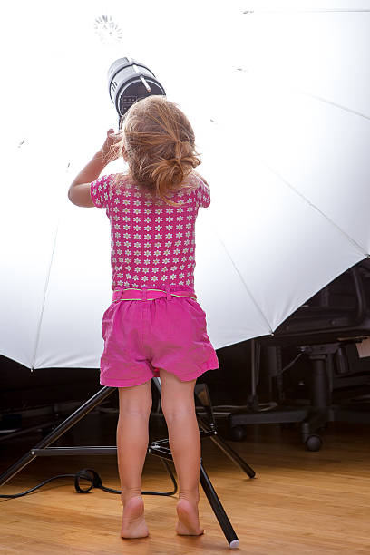 mały śliczny maluch dziewczyna regulować sprzęt oświetleniowy sett - vertical studio shot indoors pink zdjęcia i obrazy z banku zdjęć