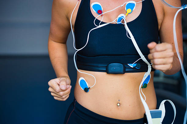 Front view of female sport women having electrocardiogram pads attached, treadmill