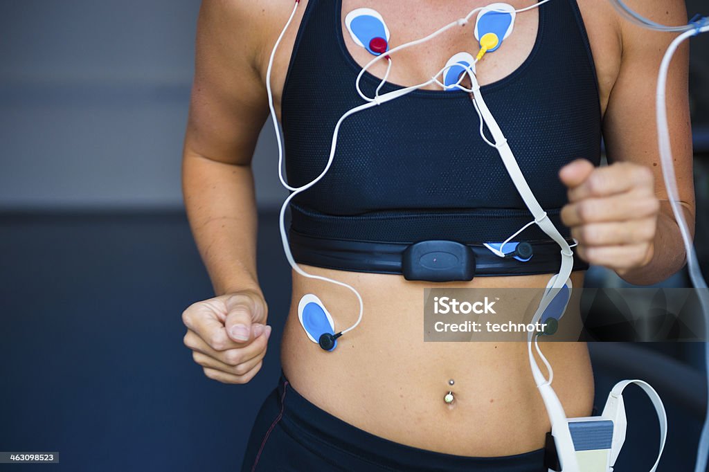 Female Athlete Performing ECG test on Treadmill Front view of female sport women having electrocardiogram pads attached, treadmill Scientific Experiment Stock Photo