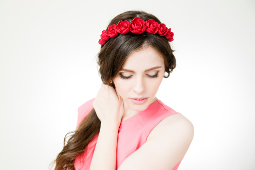 Studio portrait of a young beautiful woman with flower wreath on head. Make-up and hairstyle with flowers.