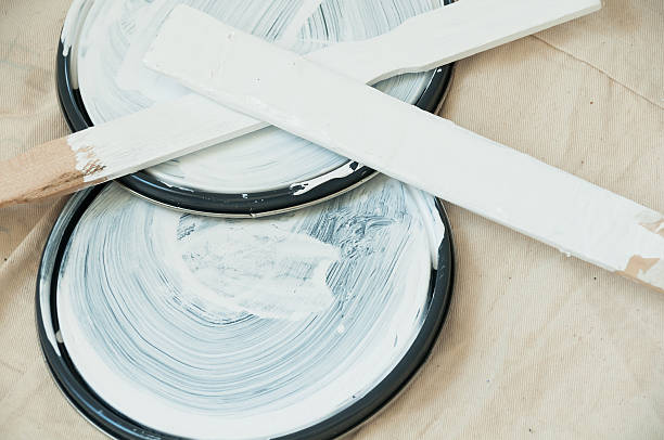 istock Two paint can lids with stir sticks on dropcloth. 463101369