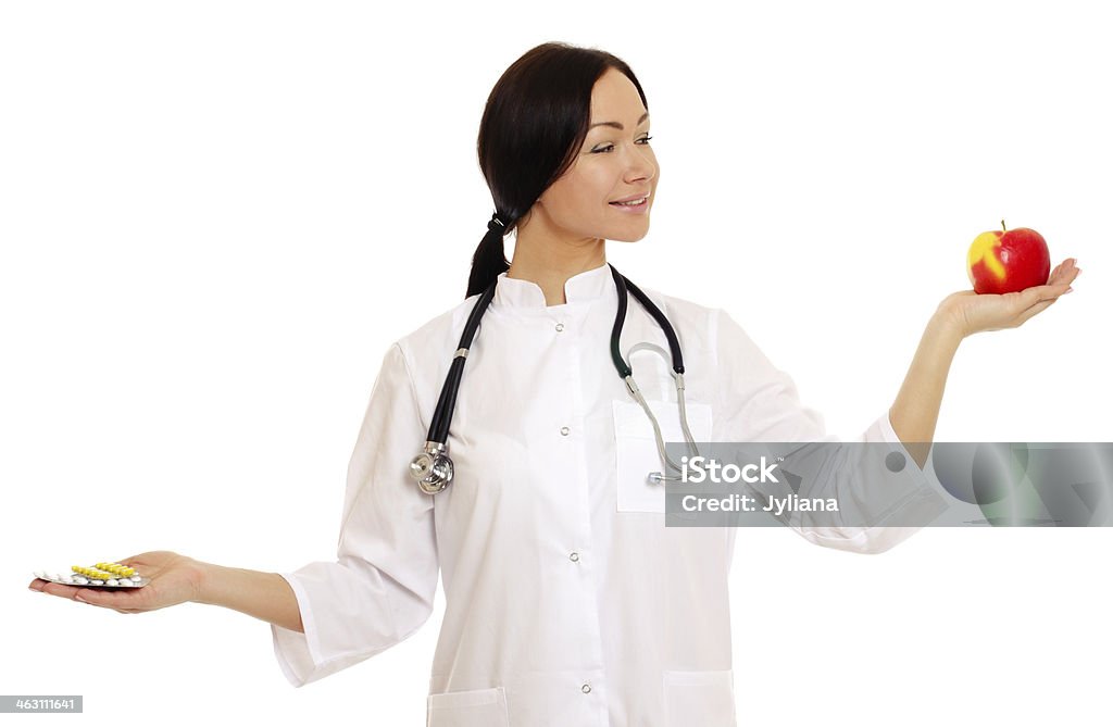 Doctor holding apple and pills - Stock Image Female doctor holding apple and bunch of tablets isolated on white background Adult Stock Photo