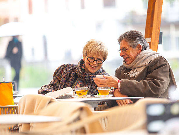 istock Senior couple smiling with cups while looking at his phone 463112885