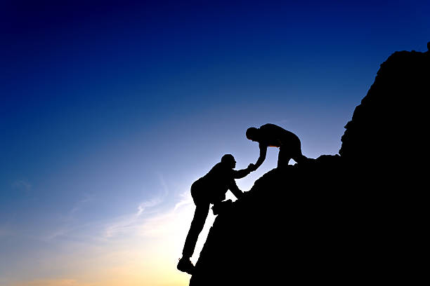 istock Silhouette of helping hand between two climbers 463114969