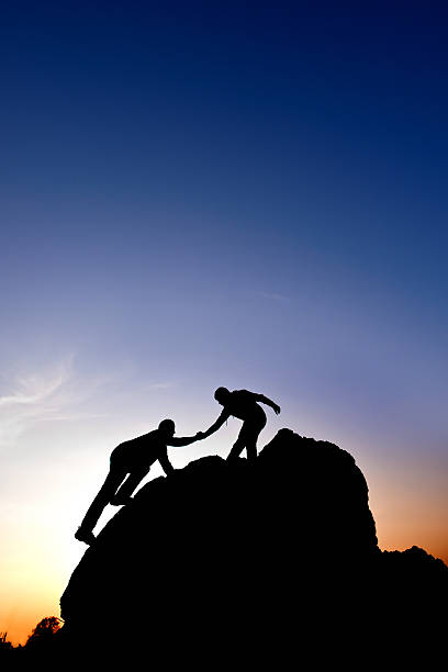 istock Silhouette of helping hand between two climbers 463115017