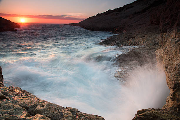 istock Waves breaking on a rocky seashore at sunset 463116071