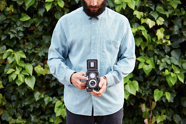 istock Young bearded hipster taking photo with TLR camera 463139343