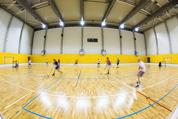 Modern gymnasium with people playing floorball
