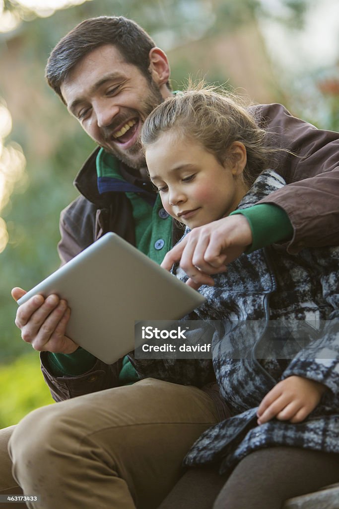 Father and Daughter With Tablet Computer Father and daughter using a tablet computer in the park Adult Stock Photo
