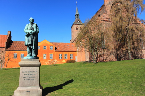 Sculpture of World Famous Danish fairy tale writer and poet Hans Christian Andersen (1805 - 1870) in front of the Sankt Knuds kirke (church) in Odense, the town where he was born.