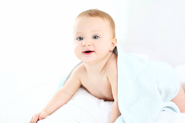 Cute baby girl on bed covered with a towel.