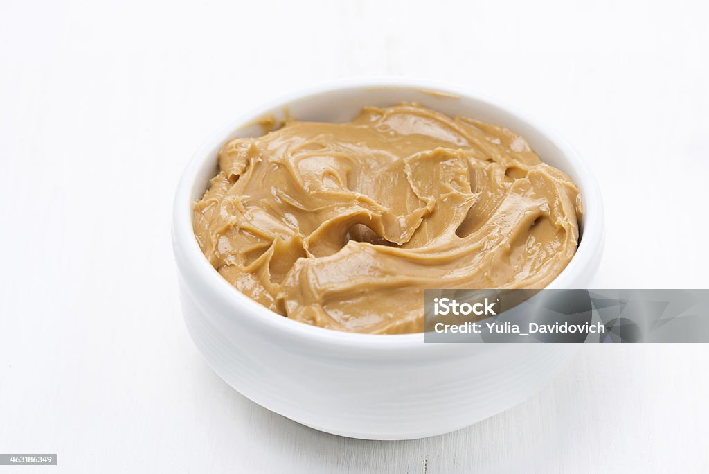 bowl of peanut butter on white wooden table bowl of peanut butter on white wooden table, close-up American Culture Stock Photo