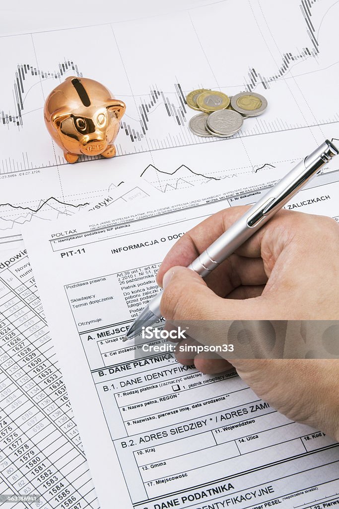 Man hand filling PIT-11 income tax forms Man hand filling PIT-11 income tax forms with piggybank and coins Tax Stock Photo