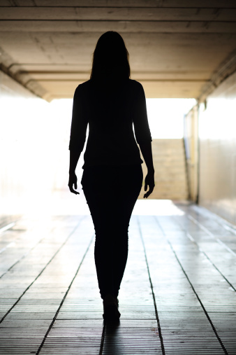 Back view of a woman silhouette walking out of the tunnel in vertical composition