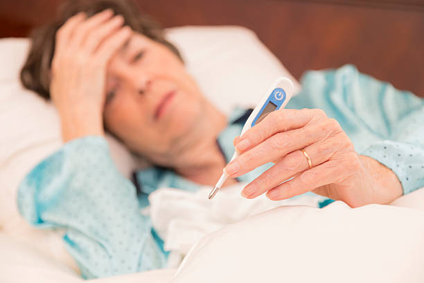 istock Healthcare:  Sick woman in bed with the flu. Thermometer. 463211889