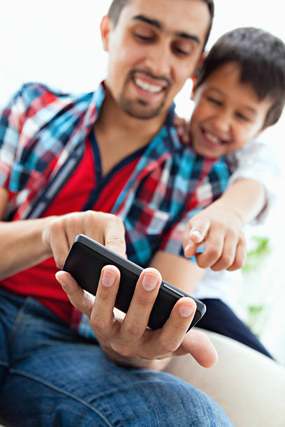 istock Smiling man and child looking at smartphone at home 463214145