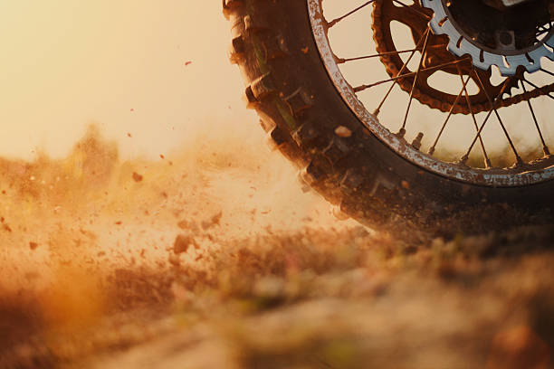 Rear wheel of a motorcross bike kicking up dirt Rear wheel of motocross bike digging the dirt, strong grain added to create atmosphere. motorized vehicle riding stock pictures, royalty-free photos & images