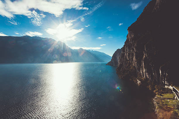 beau paysage avec soleil lac garda - water surface european alps mountain valley photos et images de collection