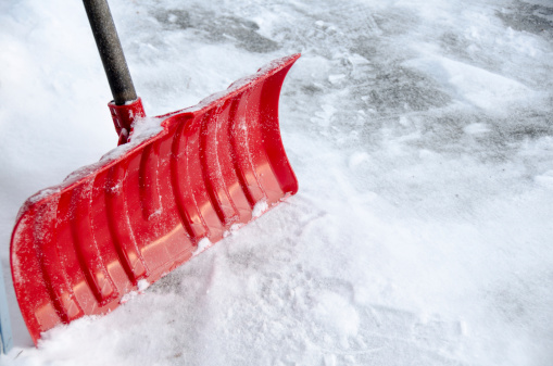 A red snow shovel with snow ... very close-up with copy space