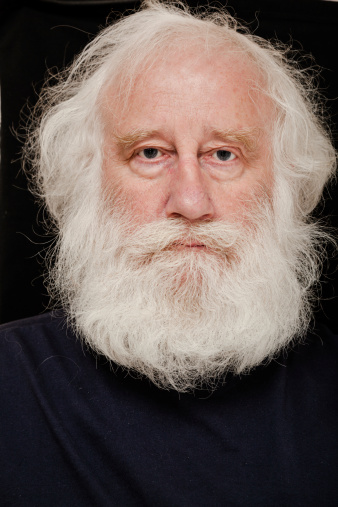 intense senior white bearded man on dark background  - against plain dark background