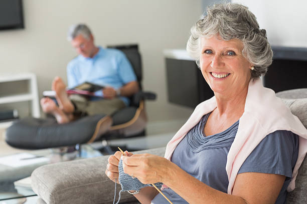 istock Smiling mature woman knitting while her husband is reading 463227965
