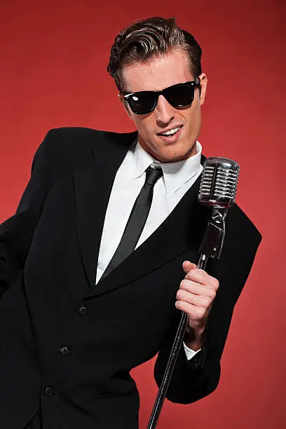 Photo of Retro fifties singer with vintage microphone and sunglasses.