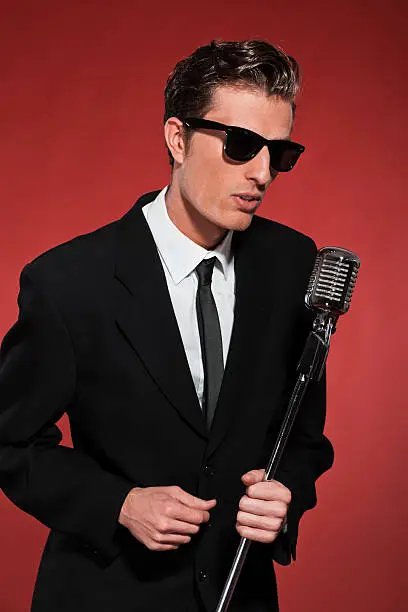Photo of Retro fifties singer with vintage microphone and sunglasses.