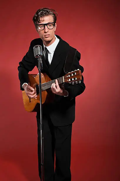 Photo of Retro fifties musician with glasses playing acoustic guitar.
