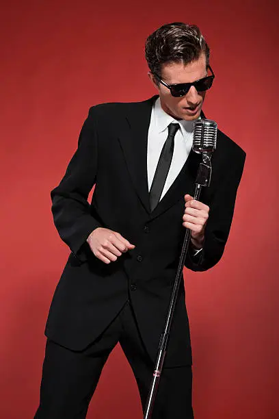 Photo of Retro fifties singer with vintage microphone and sunglasses.