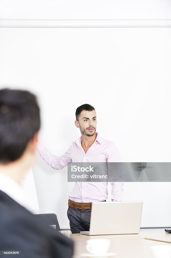 Confident business man standing by a table with laptop Handsome successful businessman standing with laptop on the table 20-29 Years Stock Photo