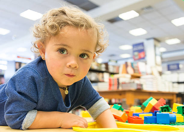 criança brincando em uma biblioteca - one baby girl only fotos imagens e fotografias de stock