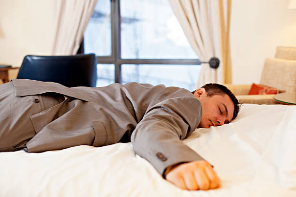 In bed at last Tired businessman sleeping on the hotel bed in the suit face down stock pictures, royalty-free photos & images