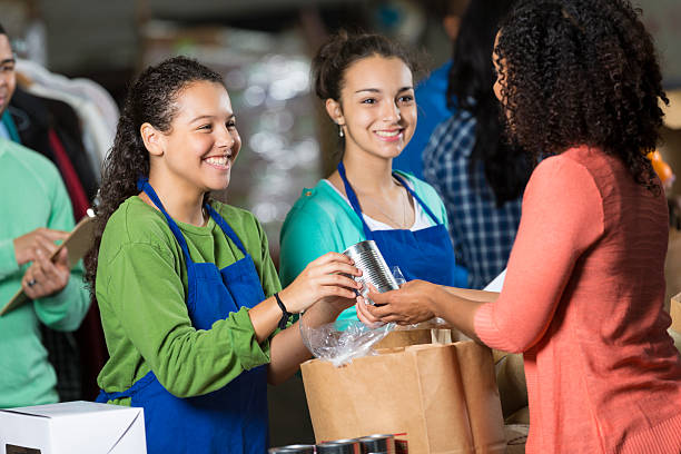 teen девушки добровольческой деятельности в продуктовый банк, получать пожертвования с продуктами - food canned food drive motivation стоковые фото и изображения