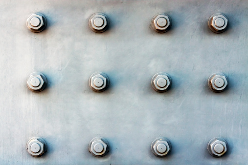 Steel plate background with large bolts, full frame horizontal composition